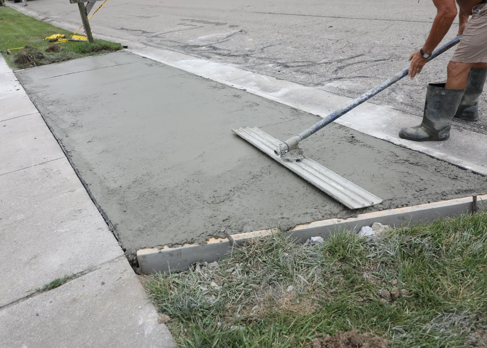 Wet concrete placed between forms for a driveway apron and leveled with a long screed